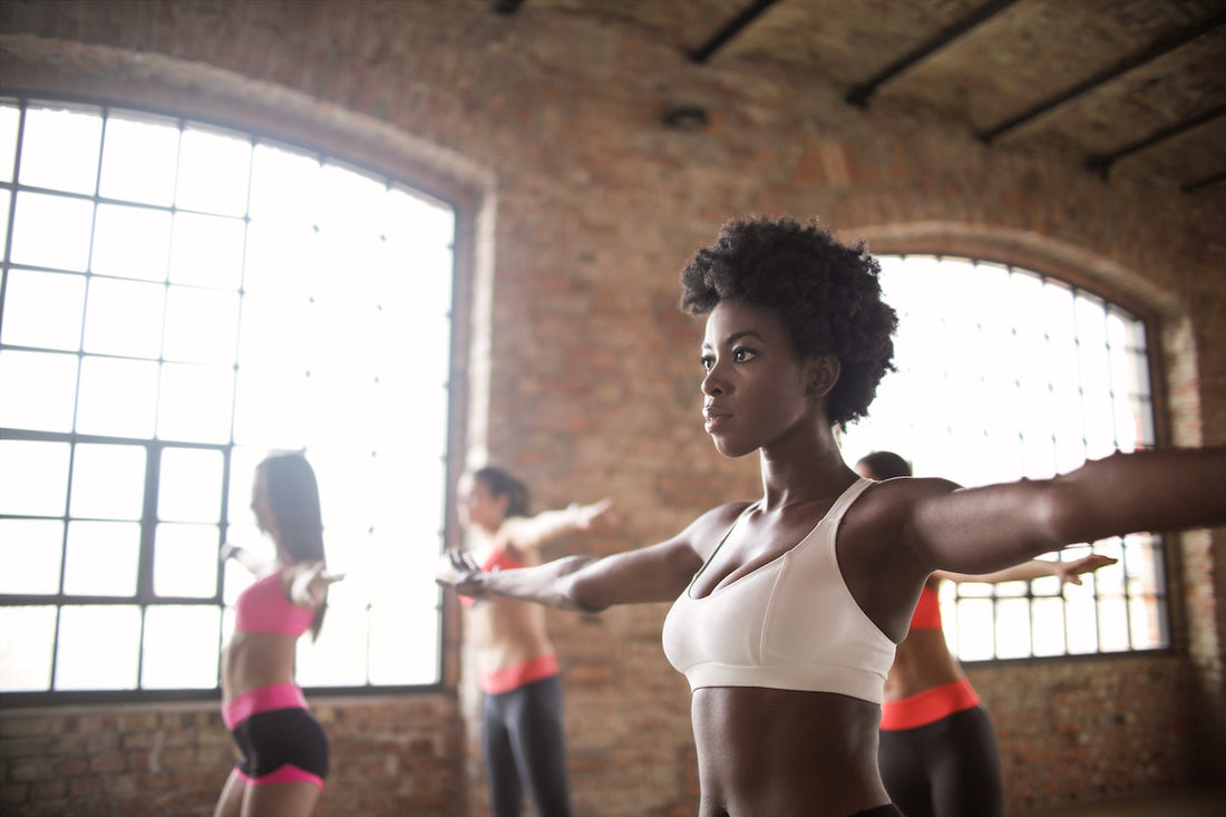 woman stretching with other athletic women in a physical wellness studio