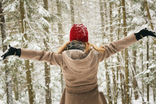 a woman dressed in warm winter clothes enjoying the snow falling on her outside