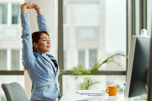 A woman performing stretches for mid back pain while sitting at her desk