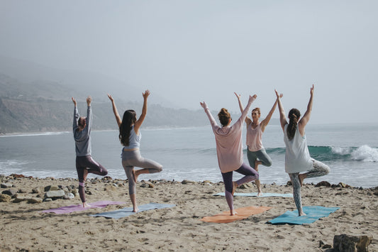 Women doing yoga on the beach for self-care