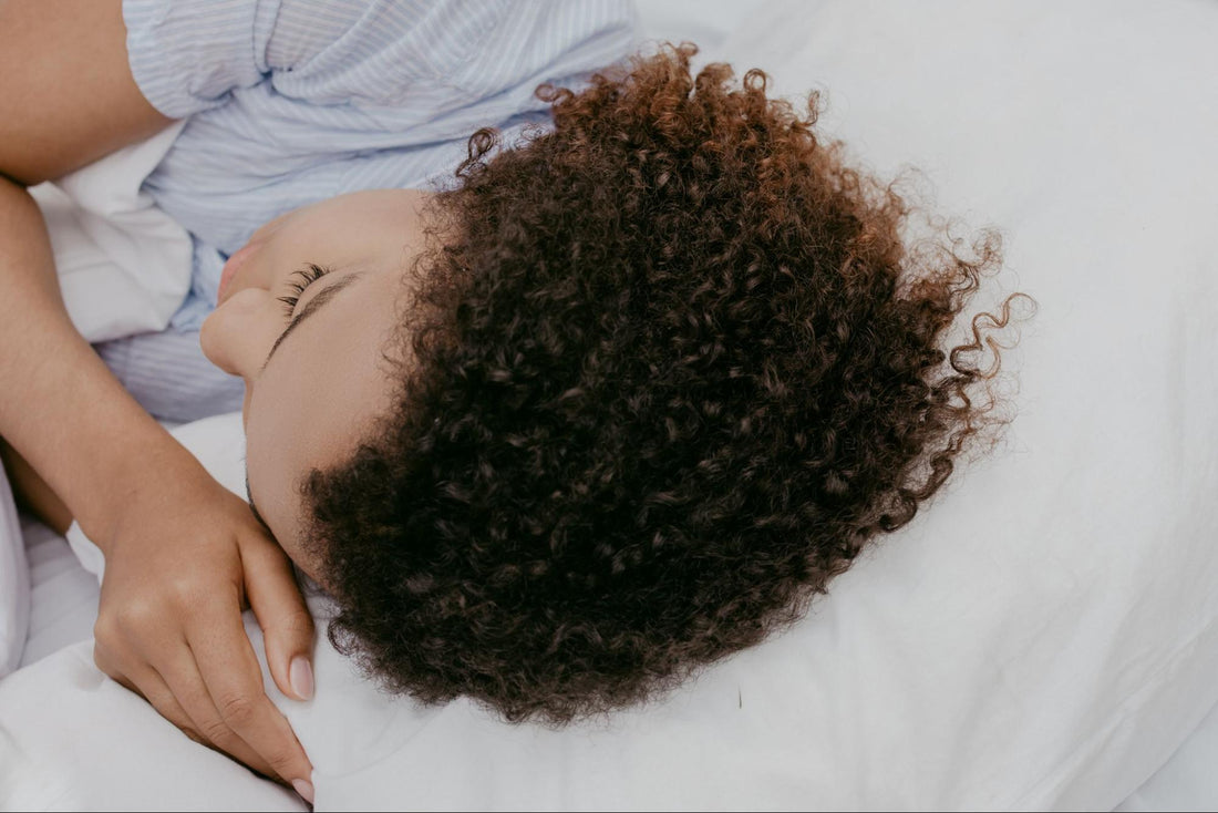 Curly-haired woman sleeping on her side with a cooling pillow