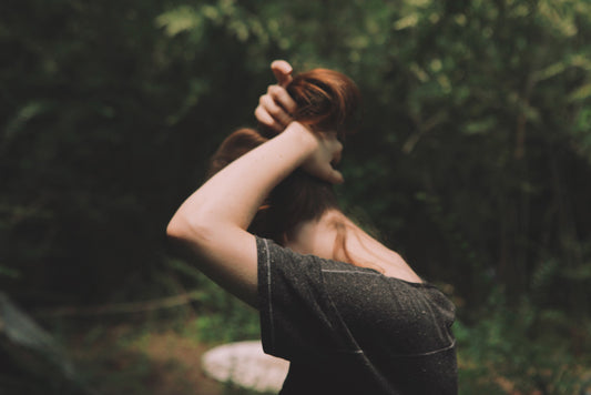 side profile of a woman outdoors holding her head with her shoulders hunched wanting a deep tissue massage at home to relieve muscle tension