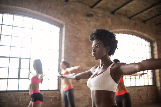 woman stretching with other athletic women in a physical wellness studio 